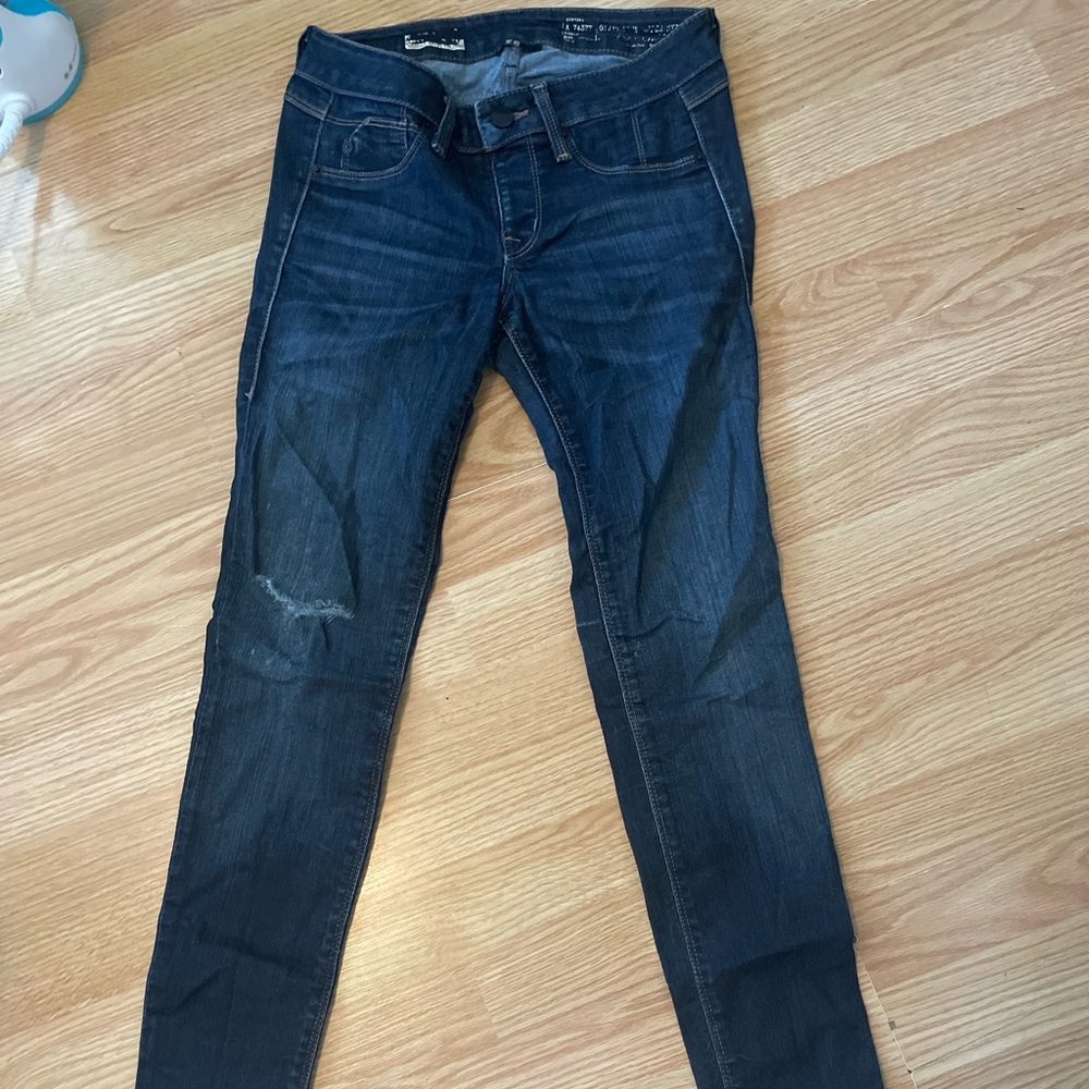Dark wash, slightly distressed skinny jeans, worn moderately
